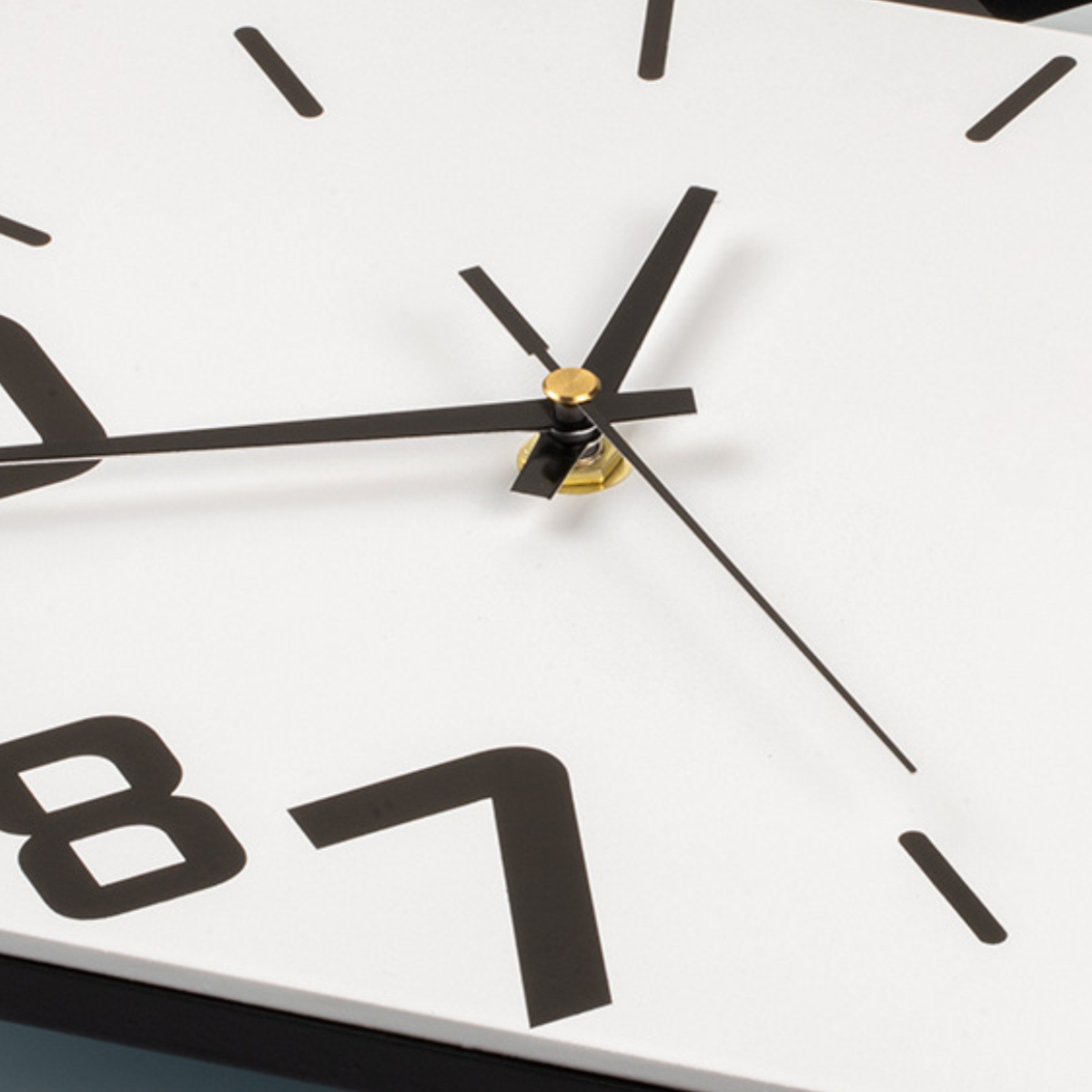 Nahaufnahme eines weißen Zifferblatts mit schwarzen Zeigern und Ziffern. Die Uhr zeigt fast 7:00 Uhr an.