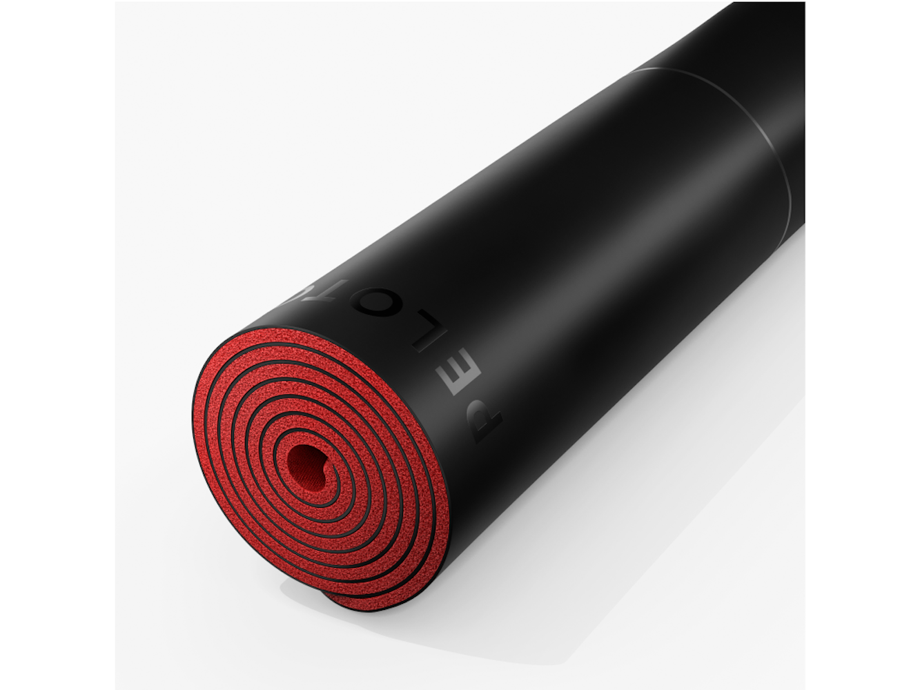 Gerollte schwarze Yogamatte mit roter Innenseite. Das Wort 'PELOTON' ist oben sichtbar. Es liegt auf einer weißen Oberfläche.