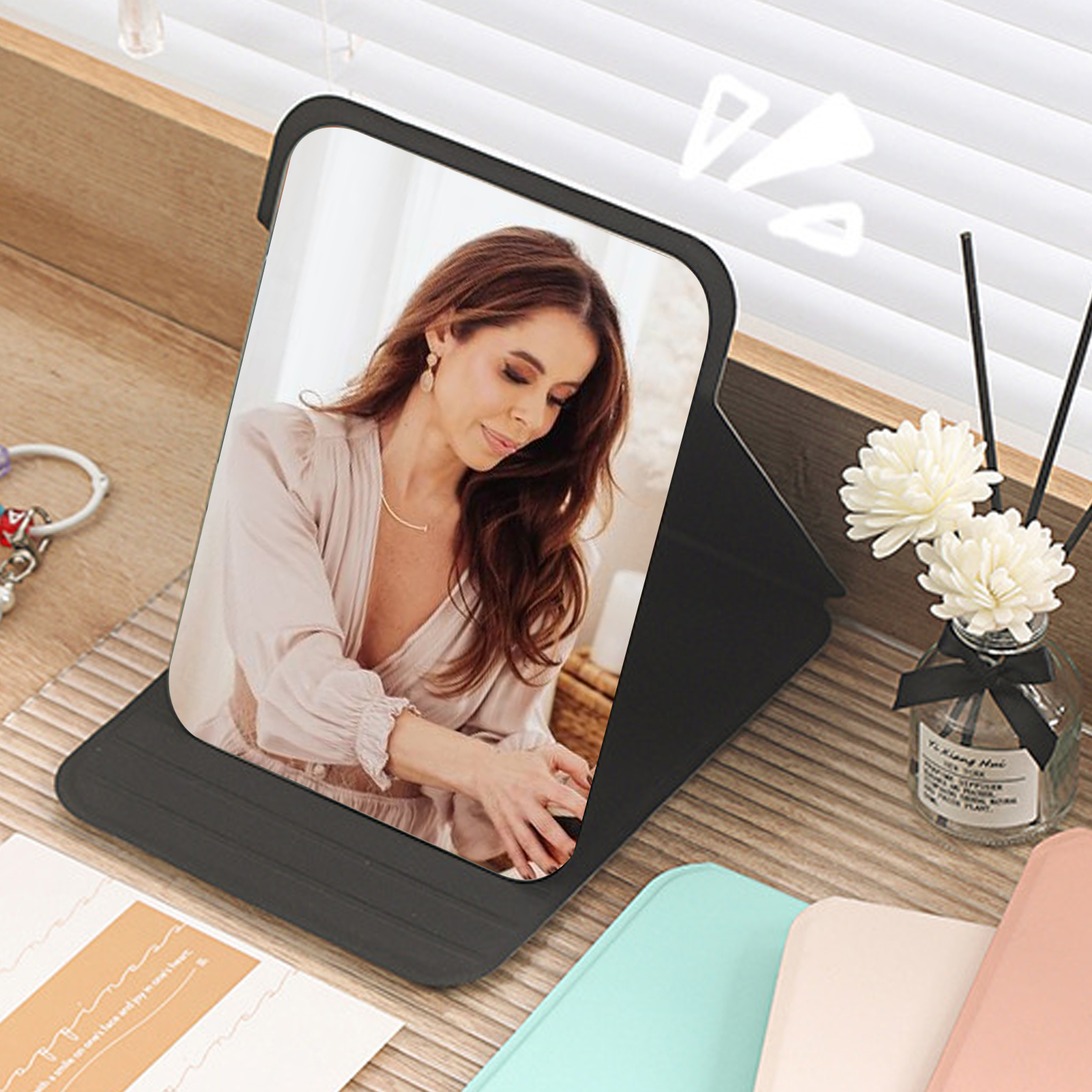 Frau schaut auf ein Tablet. Das Tablet liegt auf einem Tisch mit einem Diffusor, Blumen und Hüllen.
