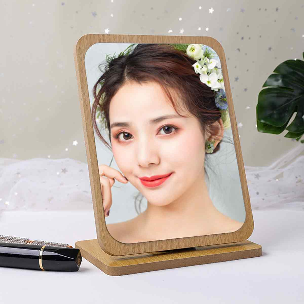 Ein gerahmtes Foto einer Frau mit Blumen im Haar. Der Rahmen ist aus Holz und ruht auf einem Holzsockel. Make-up und Lippenstift befinden sich im Vordergrund.