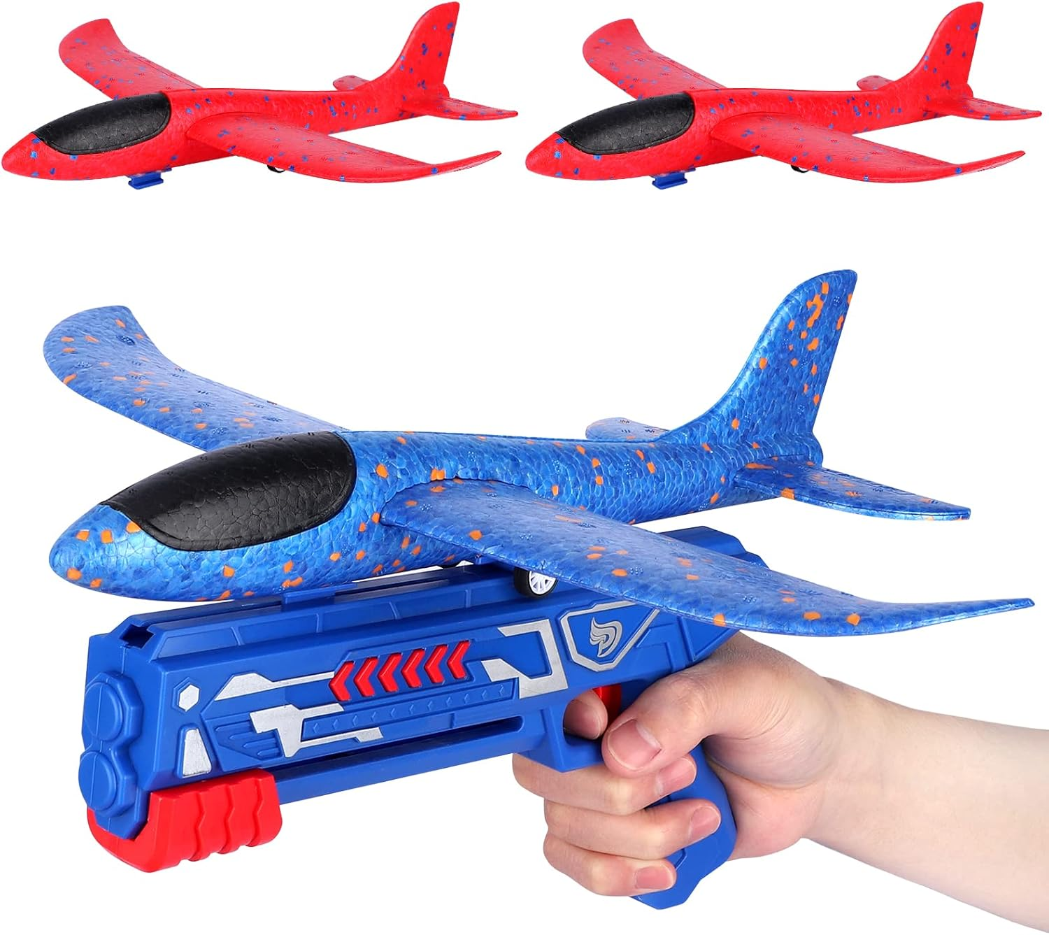 Eine Hand hält eine blaue Spielzeugpistole, die ein blaues und orangefarbenes Flugzeug startet. Im Hintergrund befinden sich zwei rote Flugzeuge.