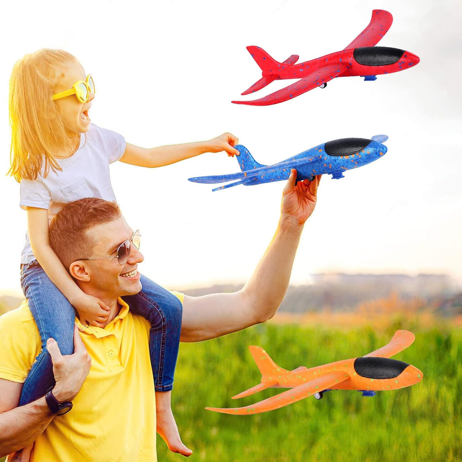 Ein Mann hält ein blaues Flugzeug, während ein Mädchen auf seinen Schultern darauf zeigt. Zwei weitere Spielzeugflugzeuge sind in der Luft: rot und orange.