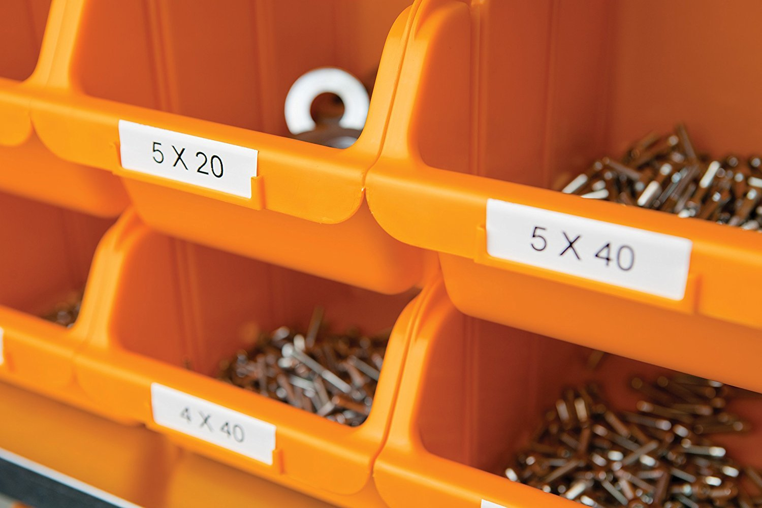 Pomarańczowe pojemniki do przechowywania są oznaczone etykietami. Zawartość obejmuje metalowe elementy złączne o różnych rozmiarach.