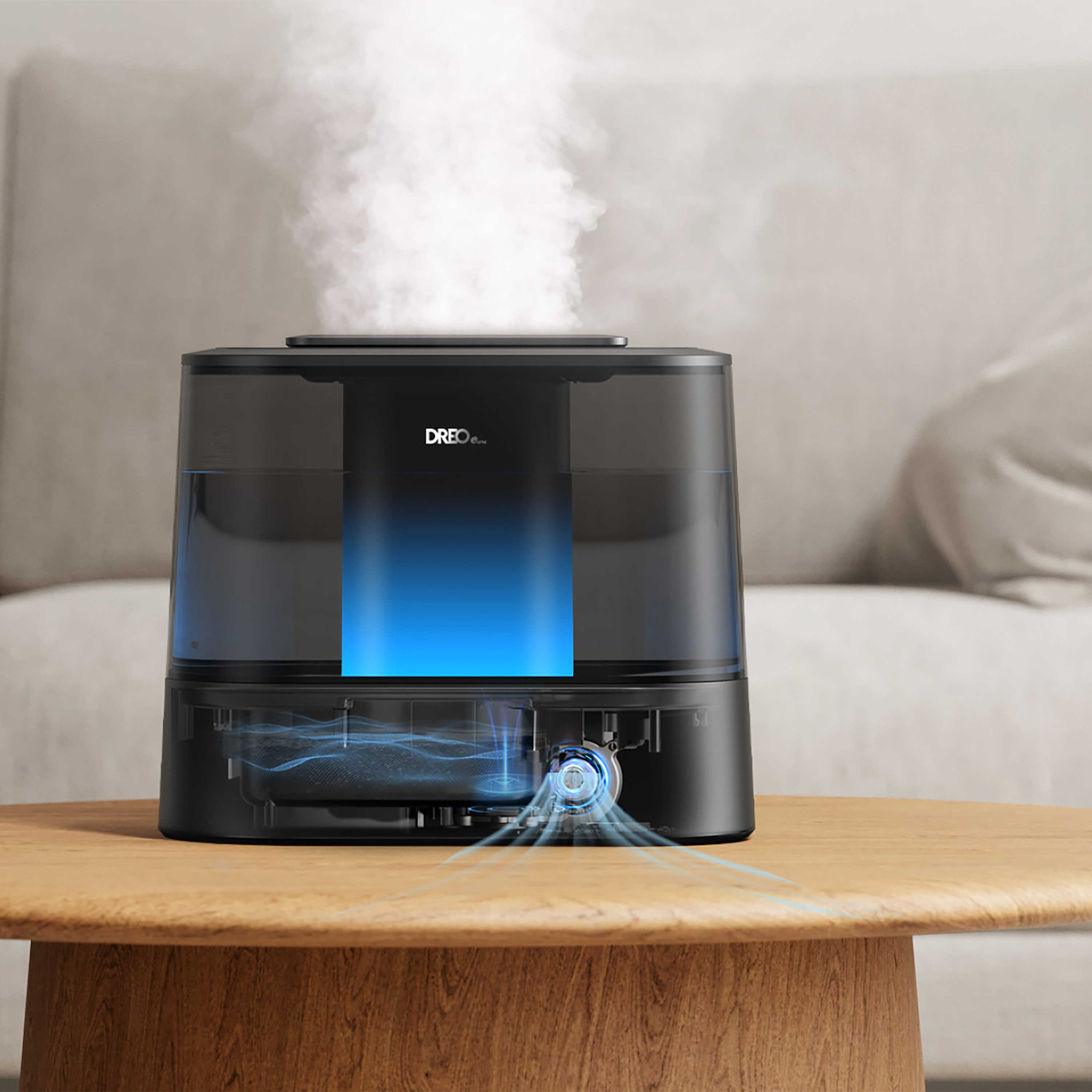 Un humidificador negro con vapor ascendente. Está sobre una mesa de madera. Un sofá está en el fondo.