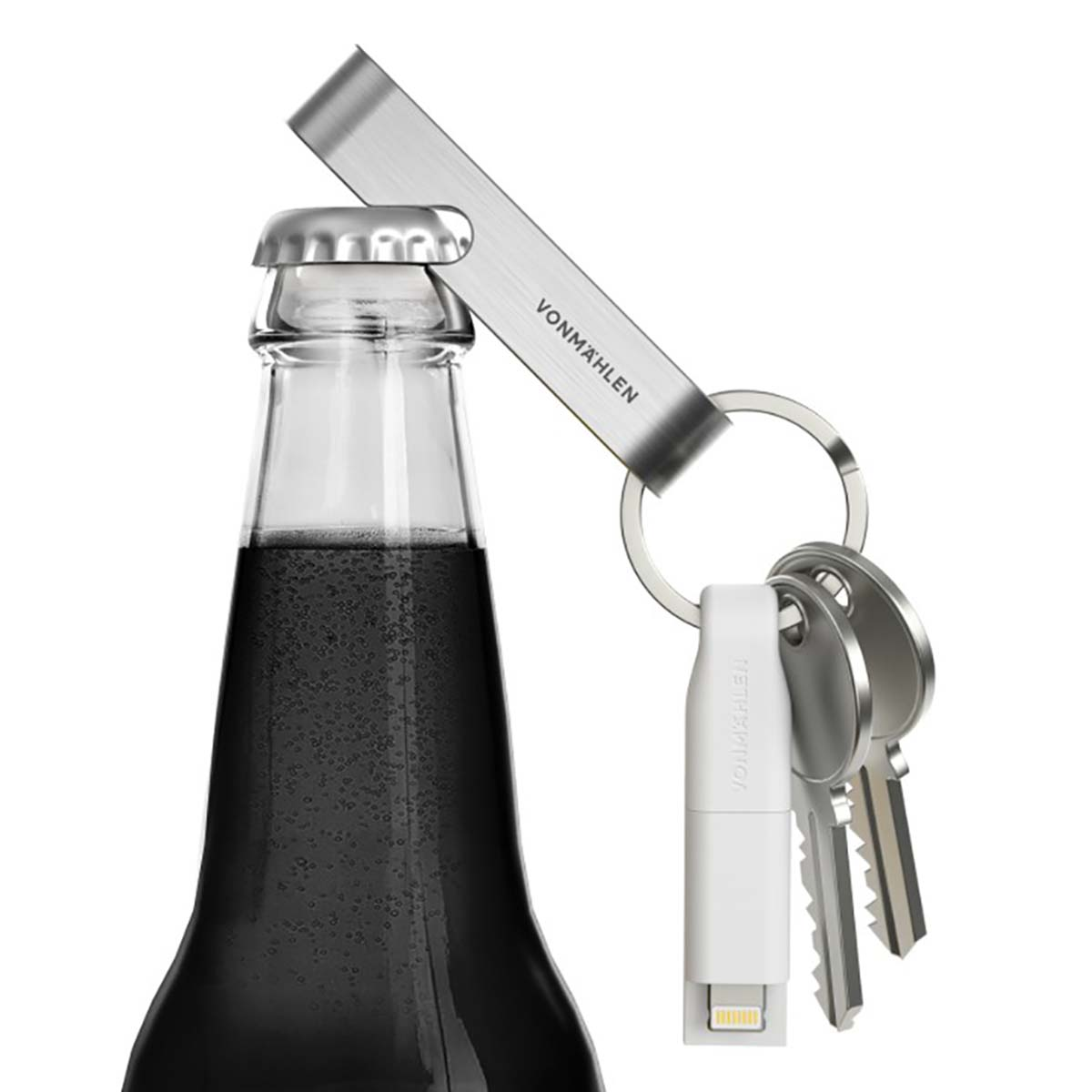 Un ouvre-bouteille enlève un bouchon. Un porte-clés contient des clés et un adaptateur USB-C blanc. La bouteille contient un liquide foncé.