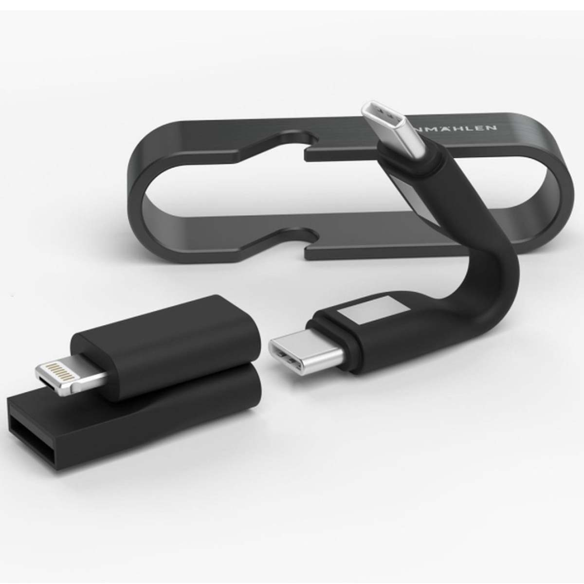 Cavi USB neri e un supporto su una superficie bianca. I cavi includono connettori USB-C e Lightning. 'NMAHLEN' stampato sul supporto.
