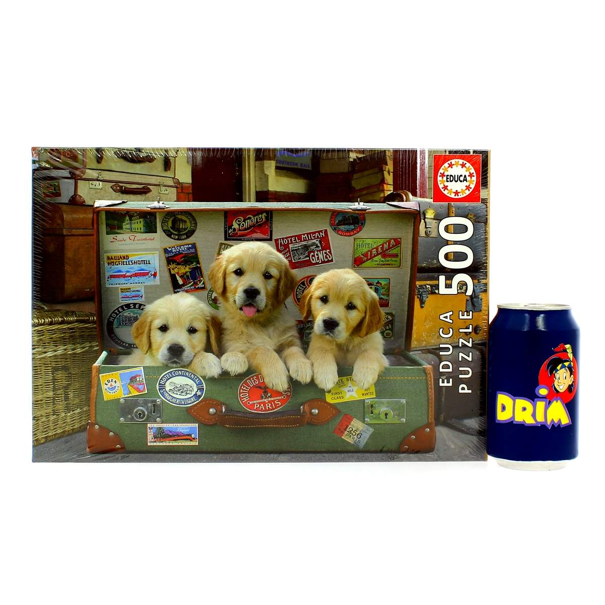 Puzzle z trzema szczeniakami golden retriever wyglądającymi z walizki. Po prawej puszka napoju Dria.