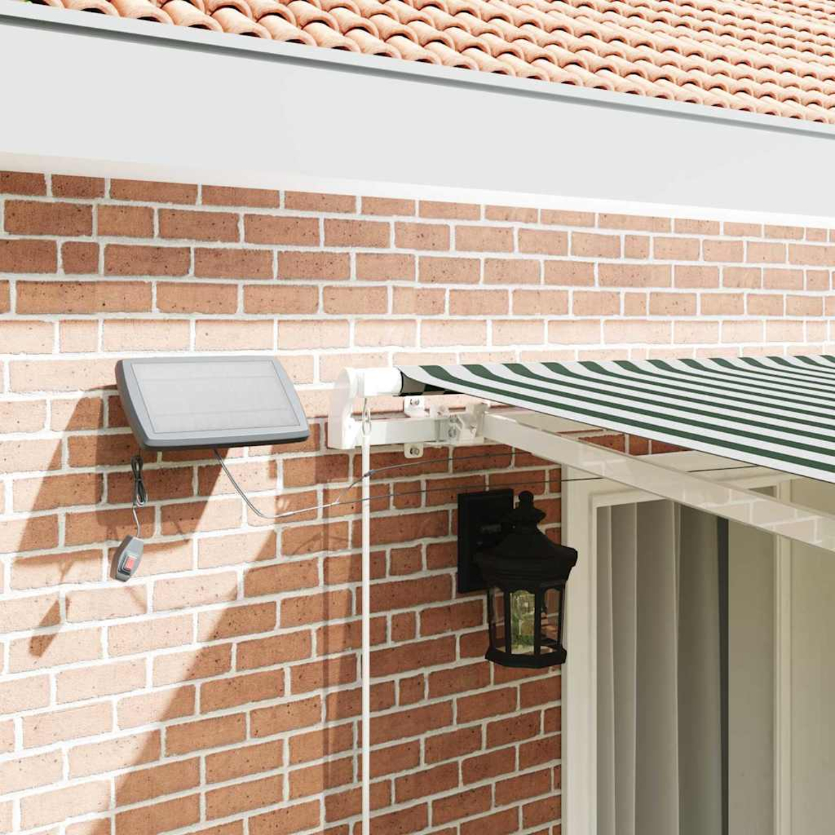 Eine Ziegelmauer mit Solarpanel, Markise und Lampe. Die Markise ist grün-weiß gestreift. Eine Lampe ist an der Wand montiert.