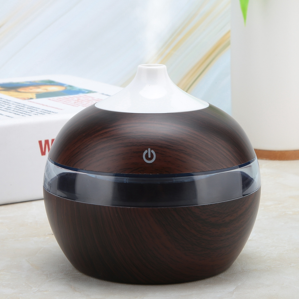 Ein brauner und weißer Diffusor für ätherische Öle mit einem Ein-/Ausschalter. Er hat ein transparentes Band und steht auf einer marmorähnlichen Oberfläche.