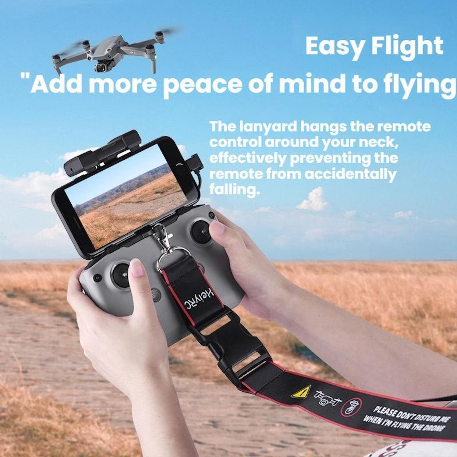 Un drone vola. Una persona tiene un telecomando con un telefono collegato. Un cordino impedisce la caduta del telecomando.