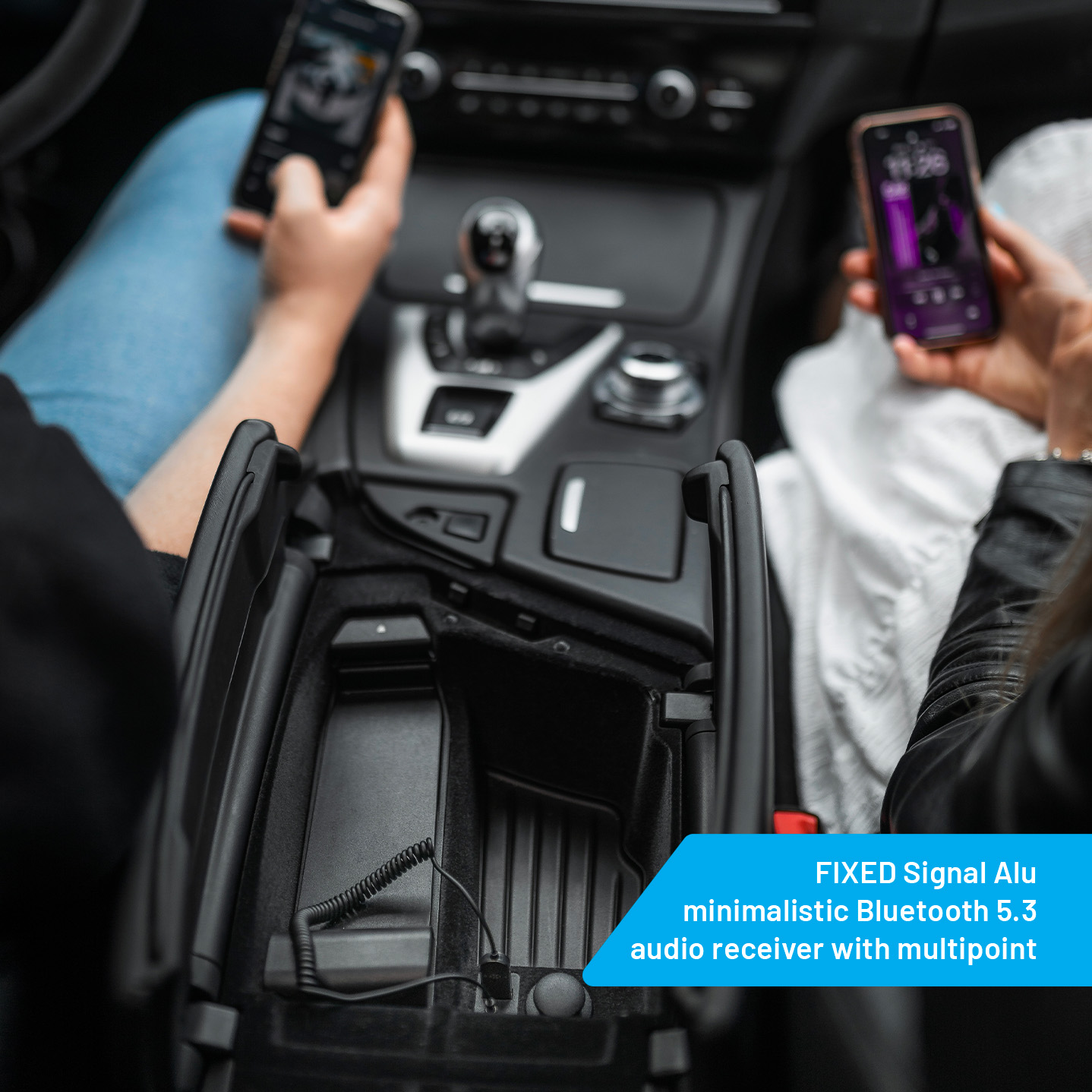 Mani che tengono telefoni dentro un'auto. Uno è collegato a un ricevitore audio nella console centrale. Il testo sullo schermo è visibile.