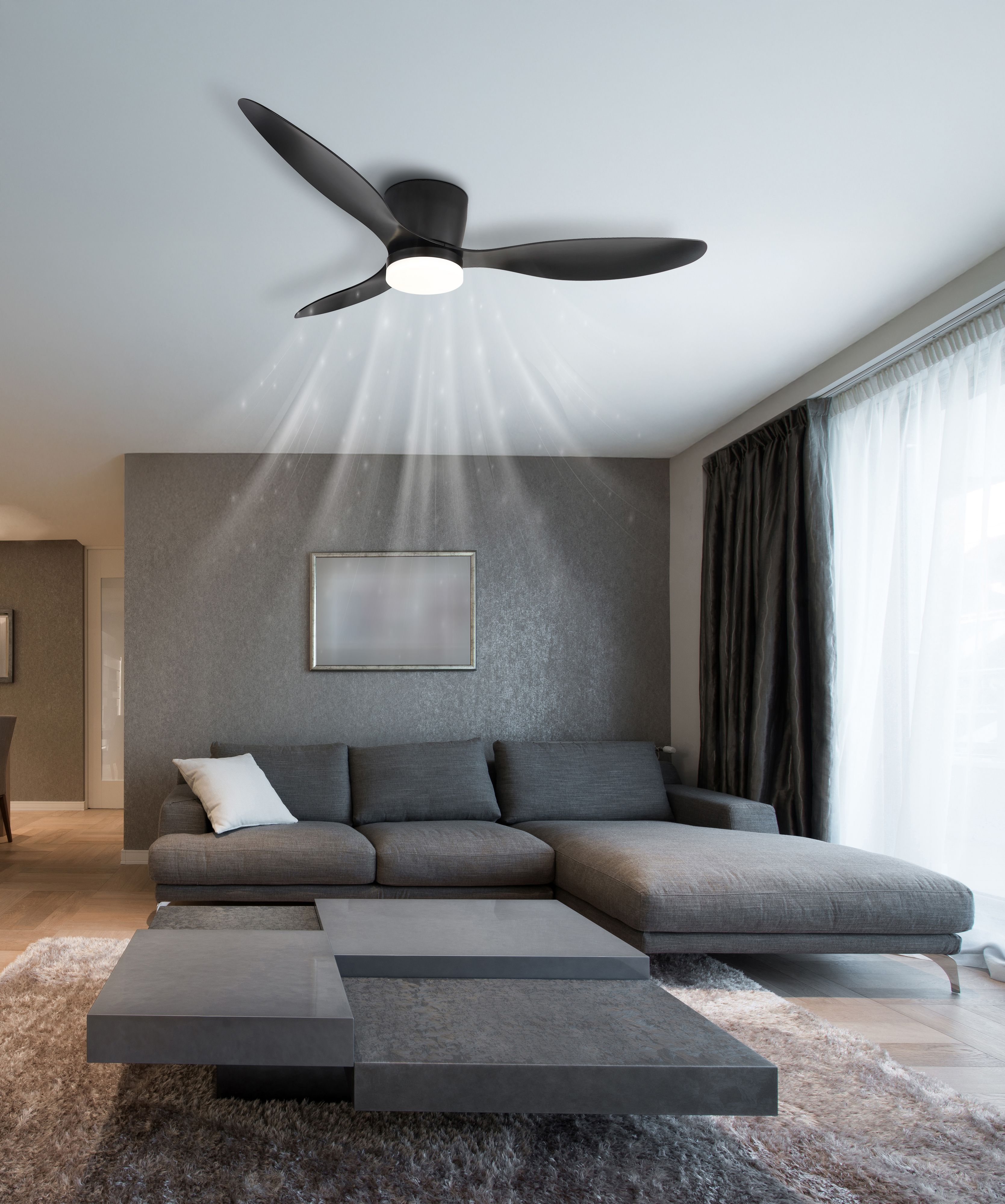 Modernes Wohnzimmer mit Deckenventilator, grauem Sofa und Couchtisch. Lichtstrahlen scheinen vom Ventilator.