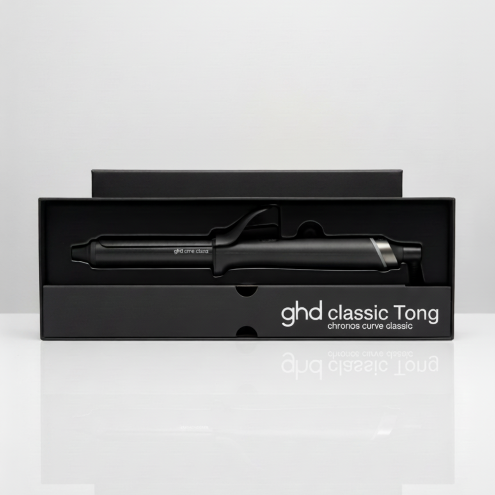Un arricciacapelli ghd classic Tong nero nella sua scatola nera. La scatola è aperta. Lo sfondo è bianco.