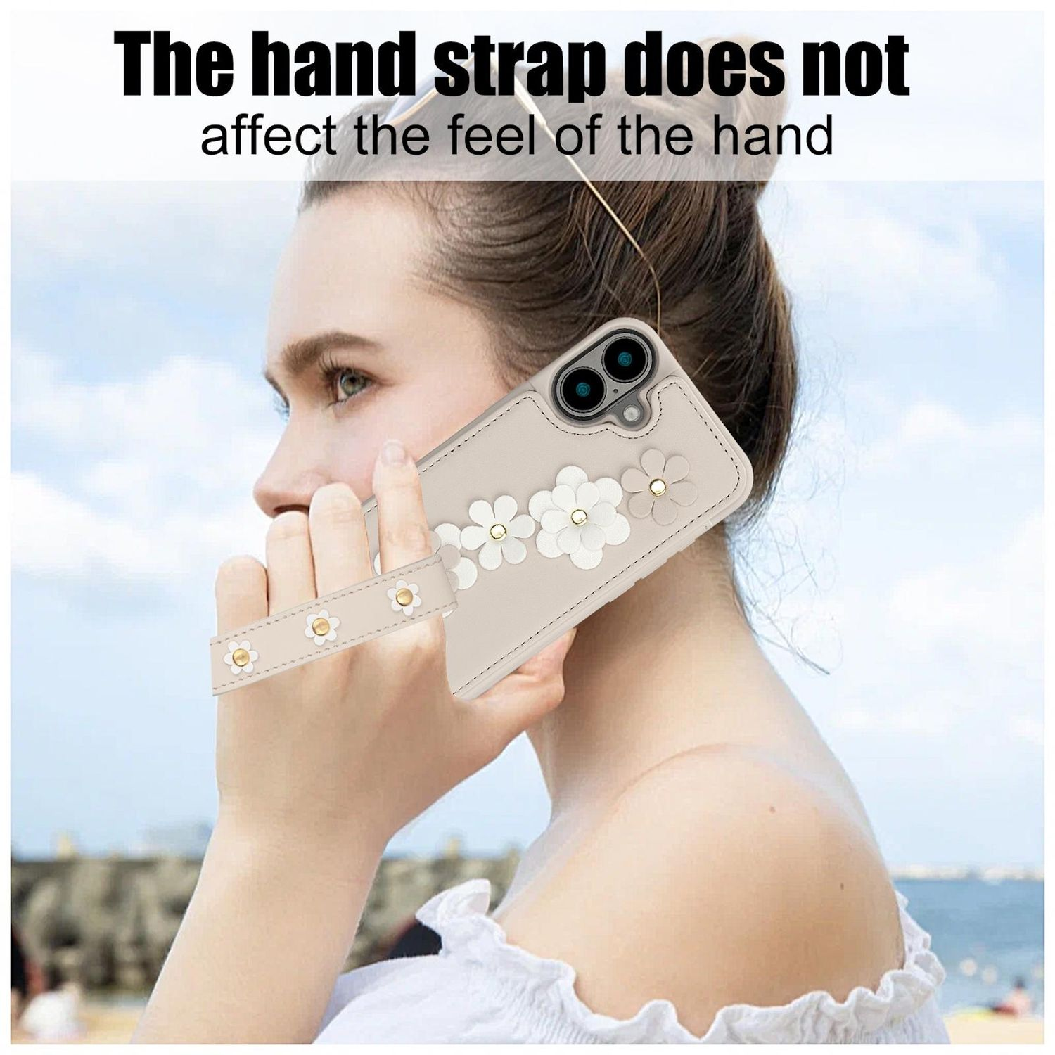 Frau hält ein Handy mit Handschlaufe. Die Handyhülle hat weiße Blumendesigns. Der Hintergrund ist eine Strandszene.
