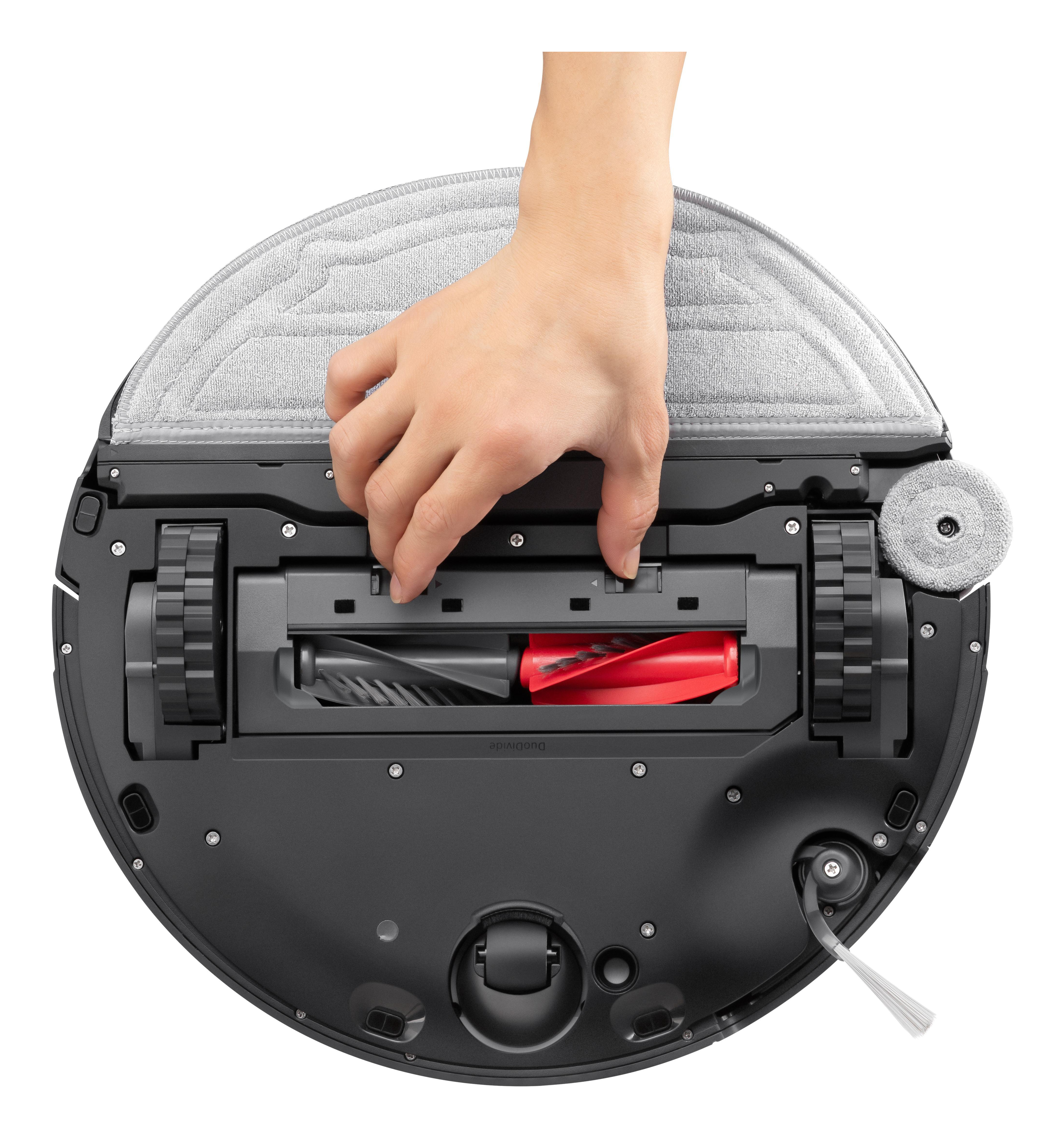 Een hand tilt een deel van een robotstofzuiger op. De reiniger heeft een zwarte behuizing en een grijze reinigingspad.