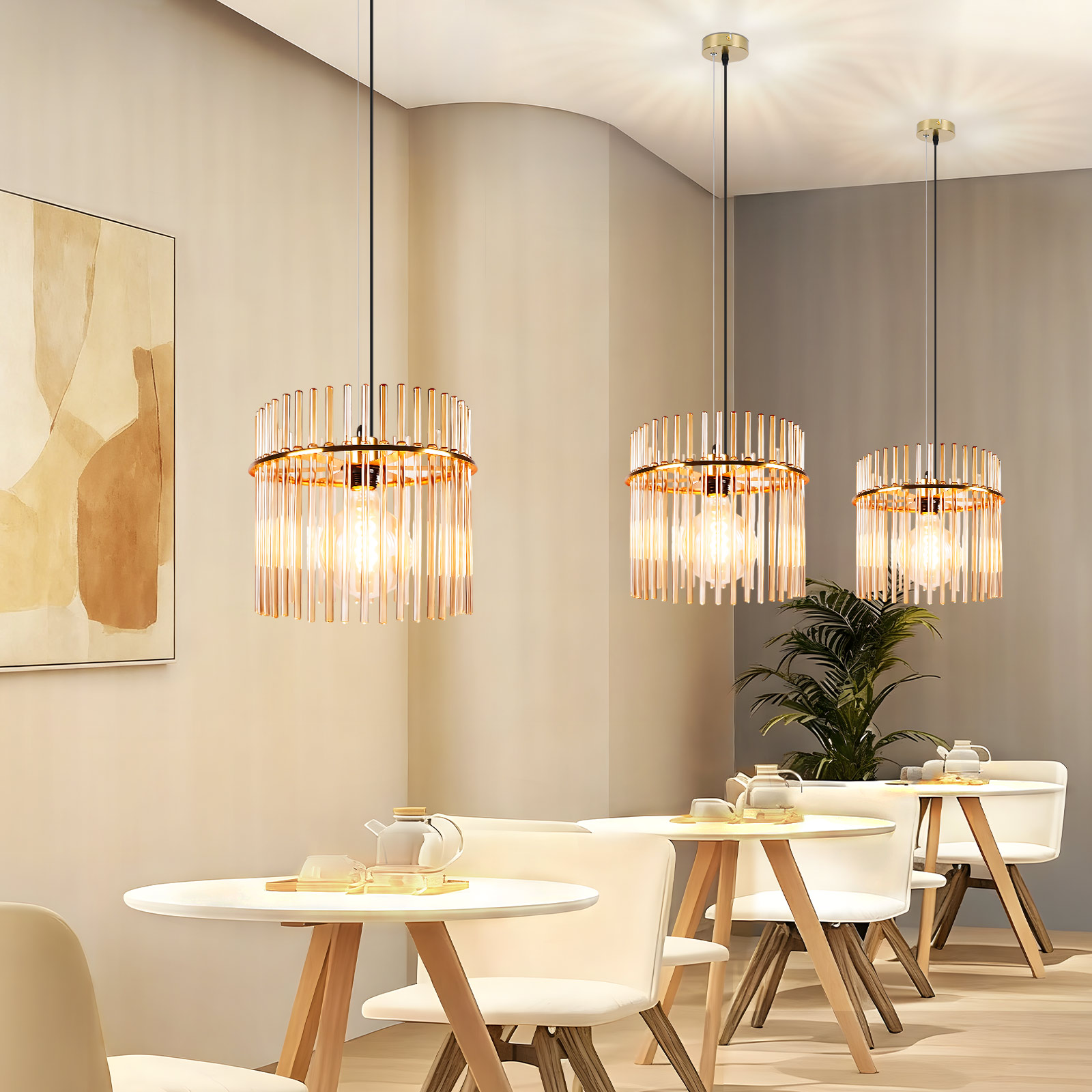 Un interior de cafetería con luces colgantes. Mesas y sillas están preparadas, con un cuadro en la pared y plantas al fondo.