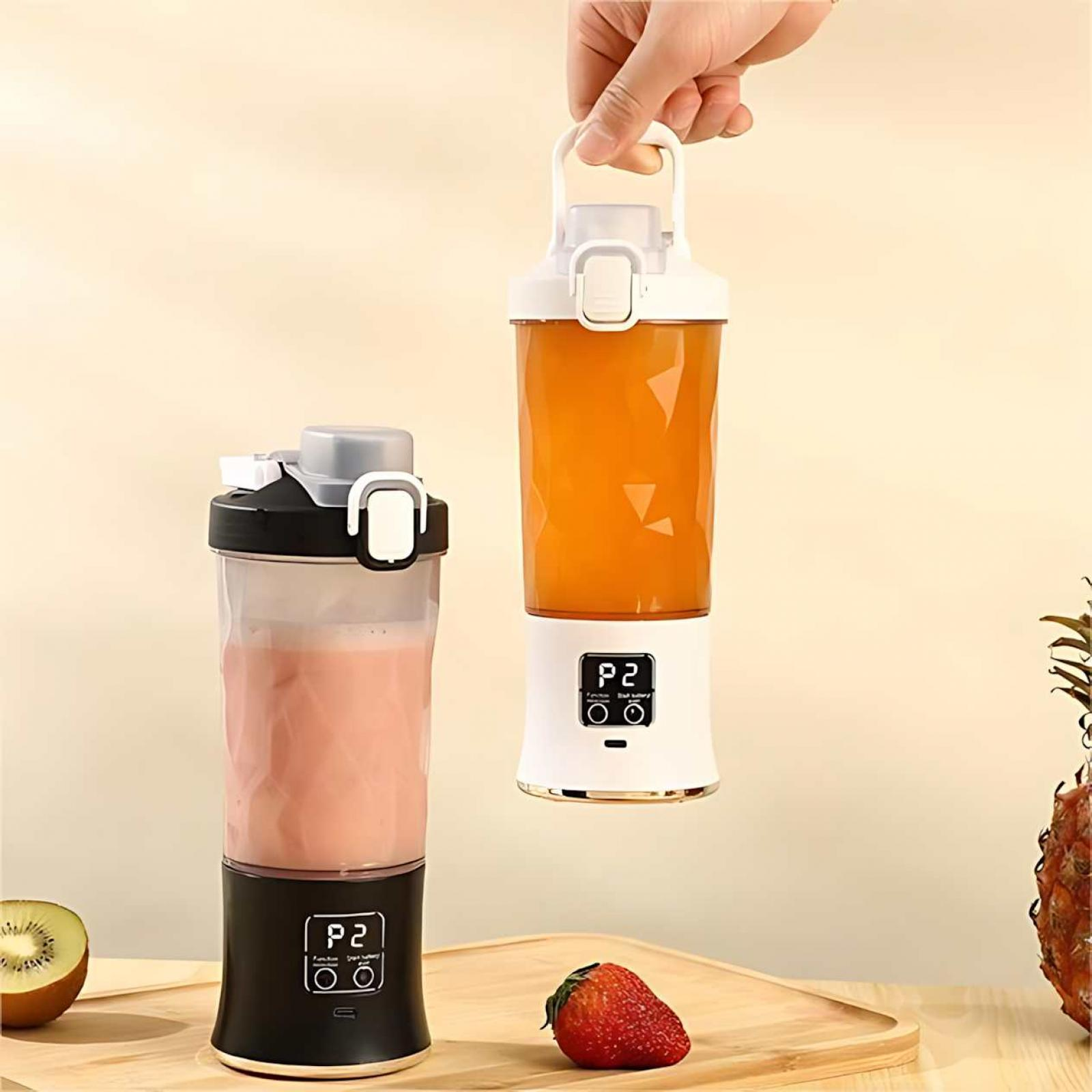 Zwei Mixer mit unterschiedlich farbigen Smoothies. Einer wird von einer Hand gehalten. Kiwi, Erdbeere und Ananas auf der Holzoberfläche.