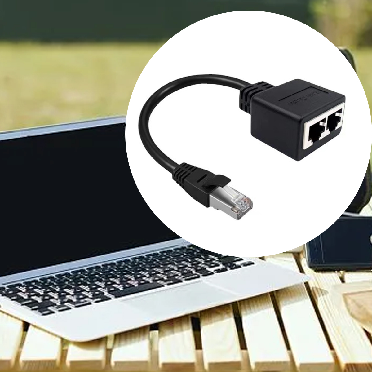 Ein schwarzes Ethernet-Kabel und -Splitter liegen auf einem Holztisch in der Nähe eines Laptops. Der Hintergrund ist grün verschwommen.