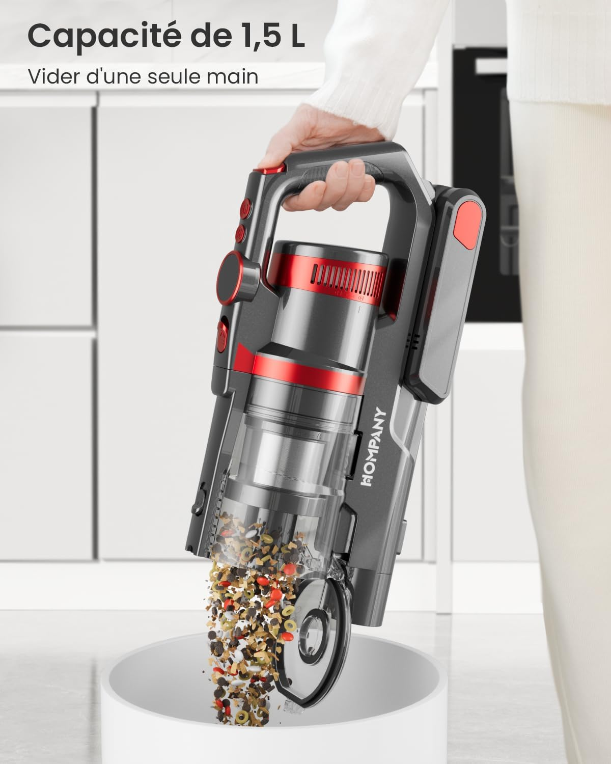Osoba opróżnia czarno-czerwony odkurzacz do białego pojemnika. Odkurzacz jest oznaczony jako 'HOMPANY' i ma przezroczysty pojemnik.