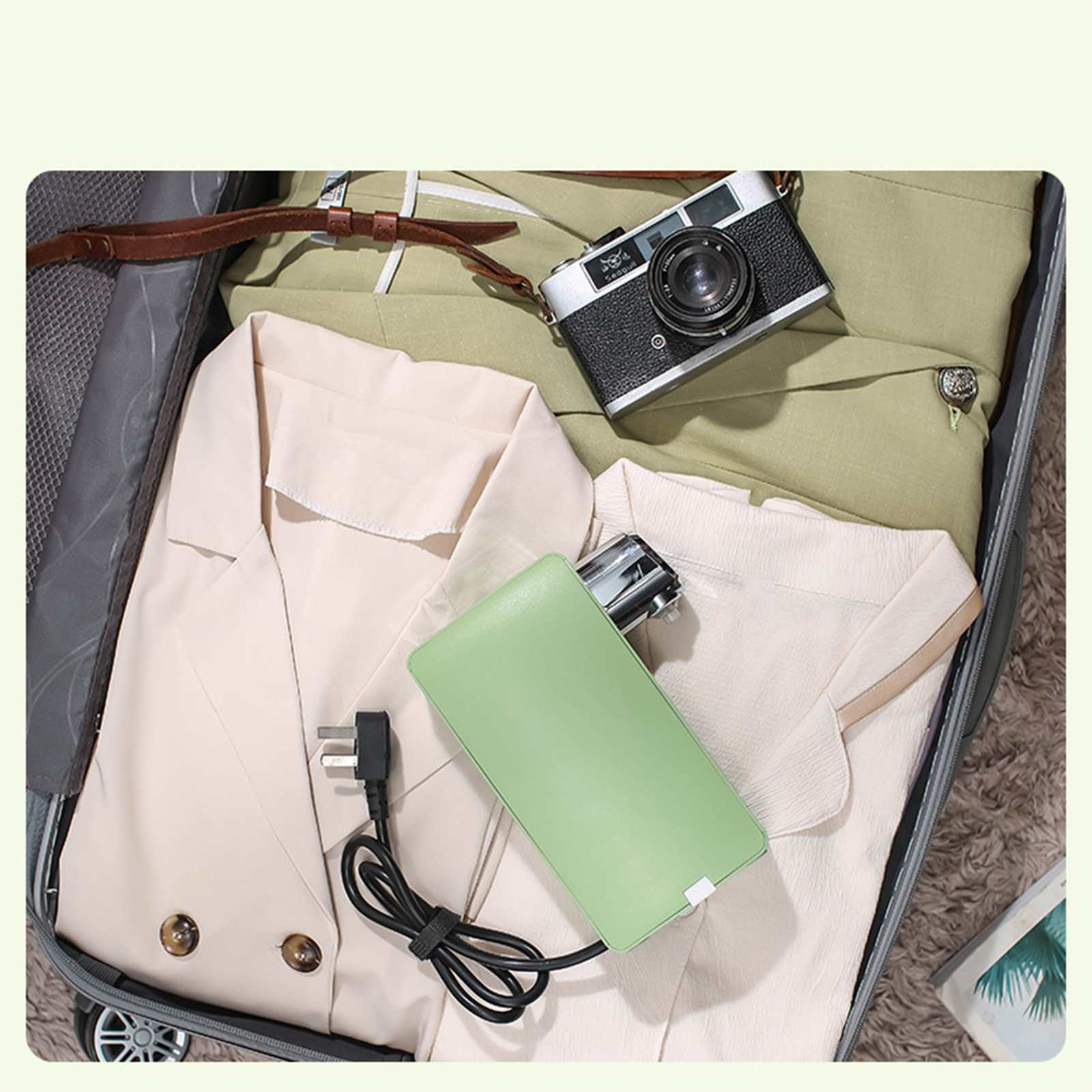 Offener Koffer mit Kleidung, Kamera und einer grünen Powerbank. Ein Stecker ist angeschlossen, die Tasche ist reisefertig.