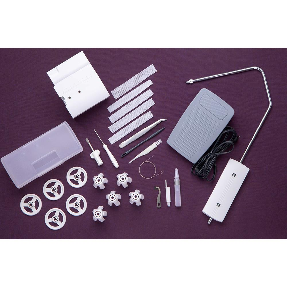 Varios accesorios de máquina de coser sobre una superficie morada, incluyendo bobinas, herramientas, pedal y un pequeño recipiente.