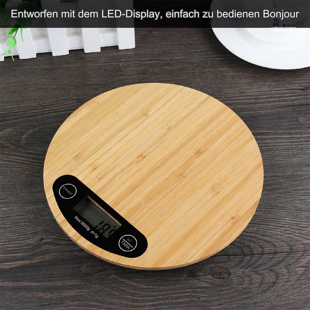 Eine runde Küchenwaage aus Holz mit digitaler Anzeige. Die Anzeige zeigt ein Gewicht. Die Waage steht auf einer dunklen Holzoberfläche.