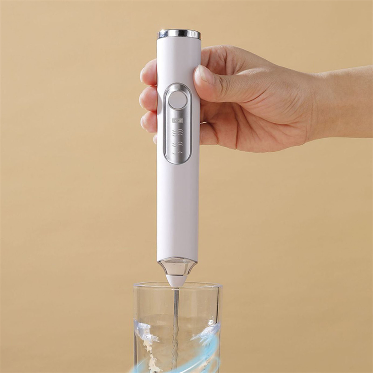 Ein weißer elektrischer Milchaufschäumer wird über einem Glas Flüssigkeit gehalten. Der Aufschäumer ist aktiviert und erzeugt einen Wirbeleffekt.