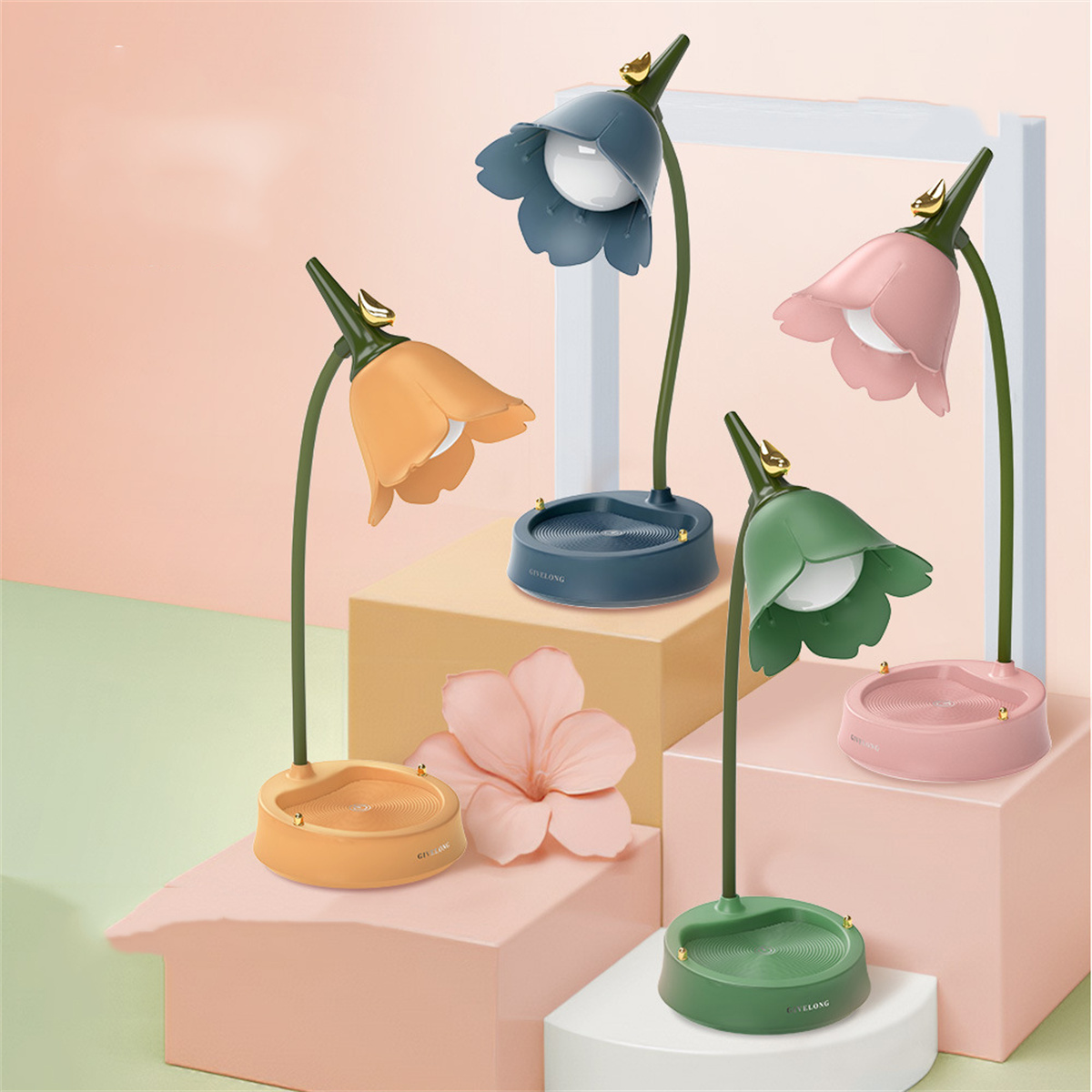 Vier blütenförmige Lampen in Orange, Blau, Rosa und Grün. Sie stehen auf einem weißen und rosa Hintergrund.