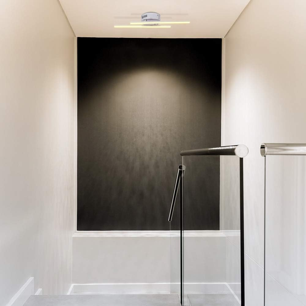 Ein Innenflur. Die Wände sind weiß, in der Mitte eine schwarze Wand. An der Decke befindet sich eine Leuchte. Glas- und Metallgeländer.