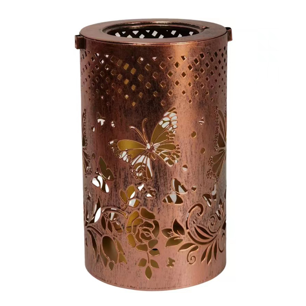 Ein kupferfarbener Kerzenhalter aus Metall mit Schmetterlings- und Blumenausschnitten. Er steht auf einer weißen Oberfläche.