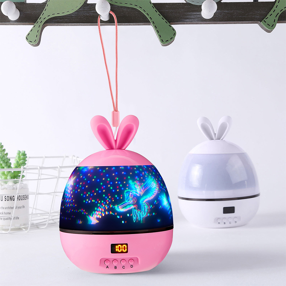 Ein rosa Projektorlampe in Hasenform mit Sternenhimmelprojektion. Es hat ein Display mit der Anzeige 100. Rechts befindet sich eine weitere weiße Lampe.