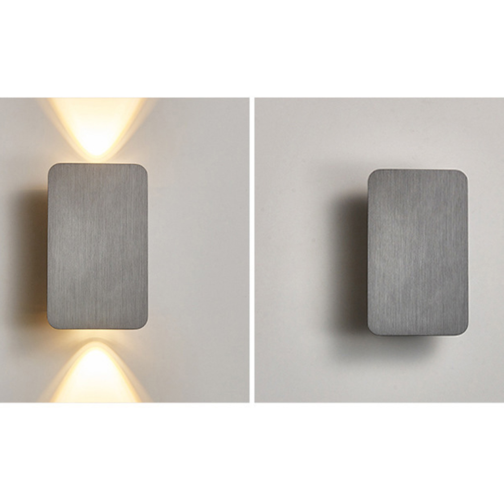 Zwei Wandleuchten aus gebürstetem Metall. Eine leuchtet und wirft Licht nach oben und unten. Die andere ist unbeleuchtet. Beide rechteckig.