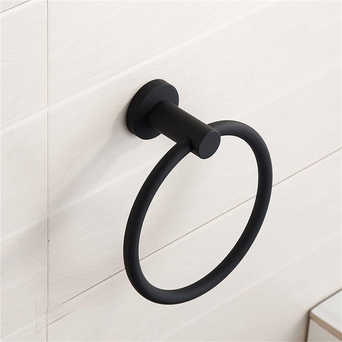 Ein schwarzer Handtuchring an einer weißen gefliesten Wand. Der Ring ist kreisförmig und aus Metall.