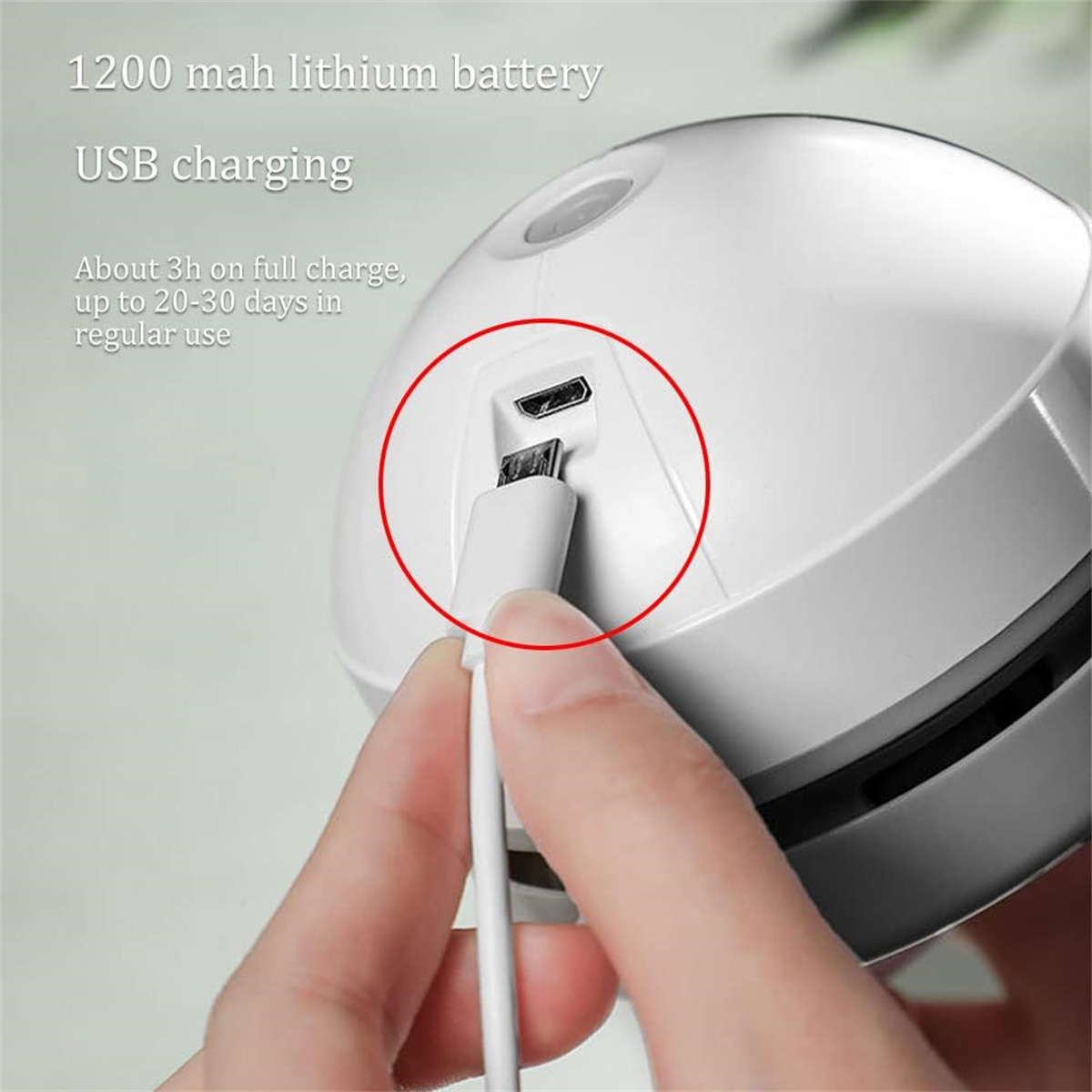 Ein weißes Gerät wird mit einem USB-Kabel aufgeladen. Das Bild zeigt den Ladeanschluss und eine Hand, die das Kabel hält.
