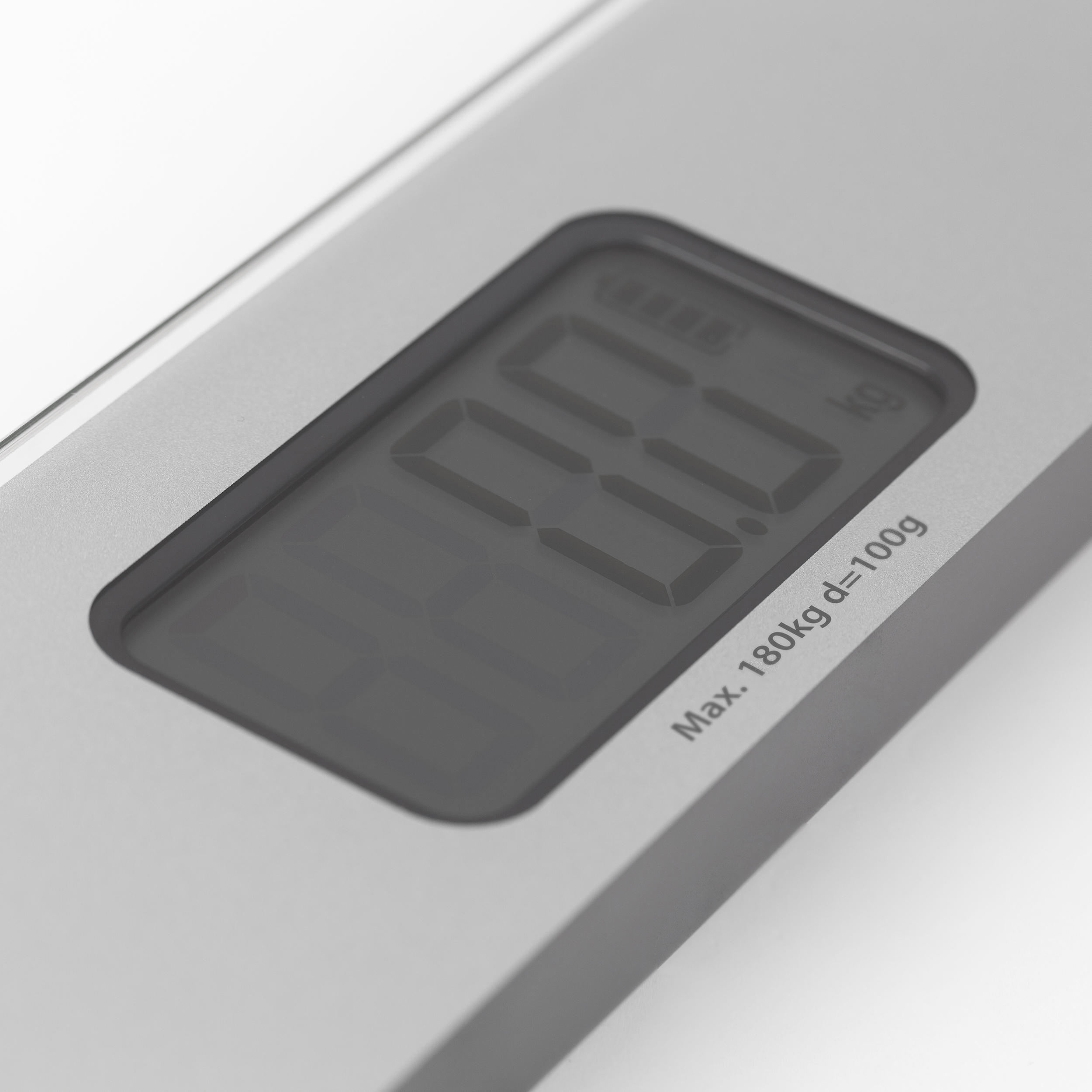 Eine digitale Waage zeigt 0,0 kg an. Sie ist silbern mit schwarzer Digitalanzeige. Text: Max. 180kg d=100g.