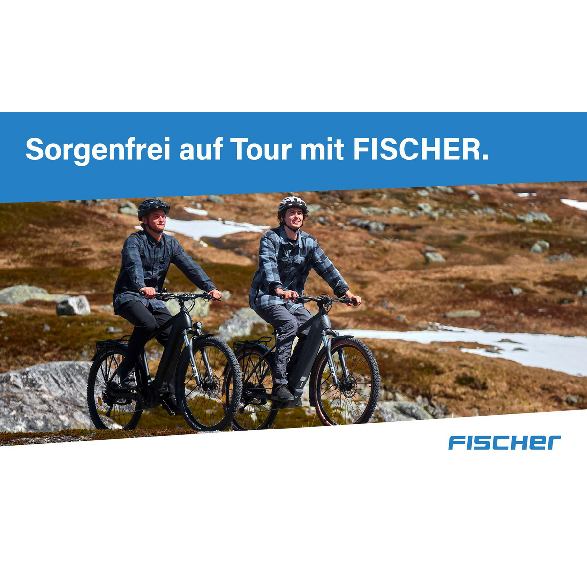 Zwei Männer fahren auf einem Bergpfad mit schwarzen E-Bikes. Sie tragen Helme und karierte Hemden. Schneeflecken und Berge im Hintergrund.