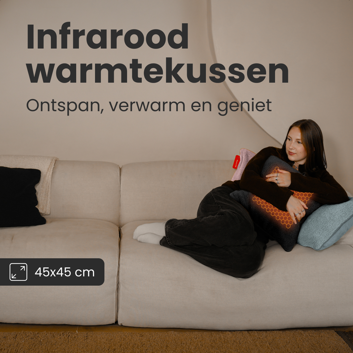 Une femme est allongée sur un canapé tenant un coussin chauffant. Il a un motif en nid d'abeille. Le texte dit 'Infrarood warmtekussen', 45x45 cm.