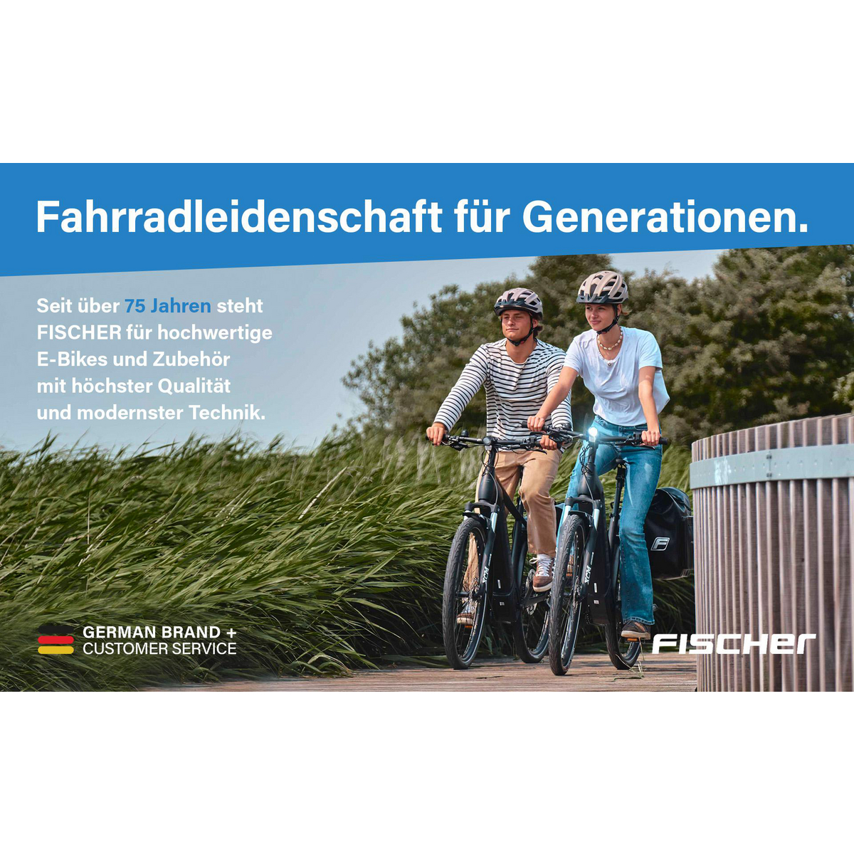 Zwei Personen fahren E-Bikes auf einem Holzweg. Sie tragen Helme. Grüne Pflanzen und ein Zaun sind im Hintergrund. Die Marke ist FISCHER.