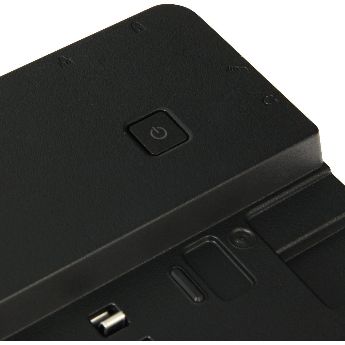 Primo piano di una docking station nera. Il pulsante di accensione e altre piccole icone sono visibili. Lo sfondo è bianco.