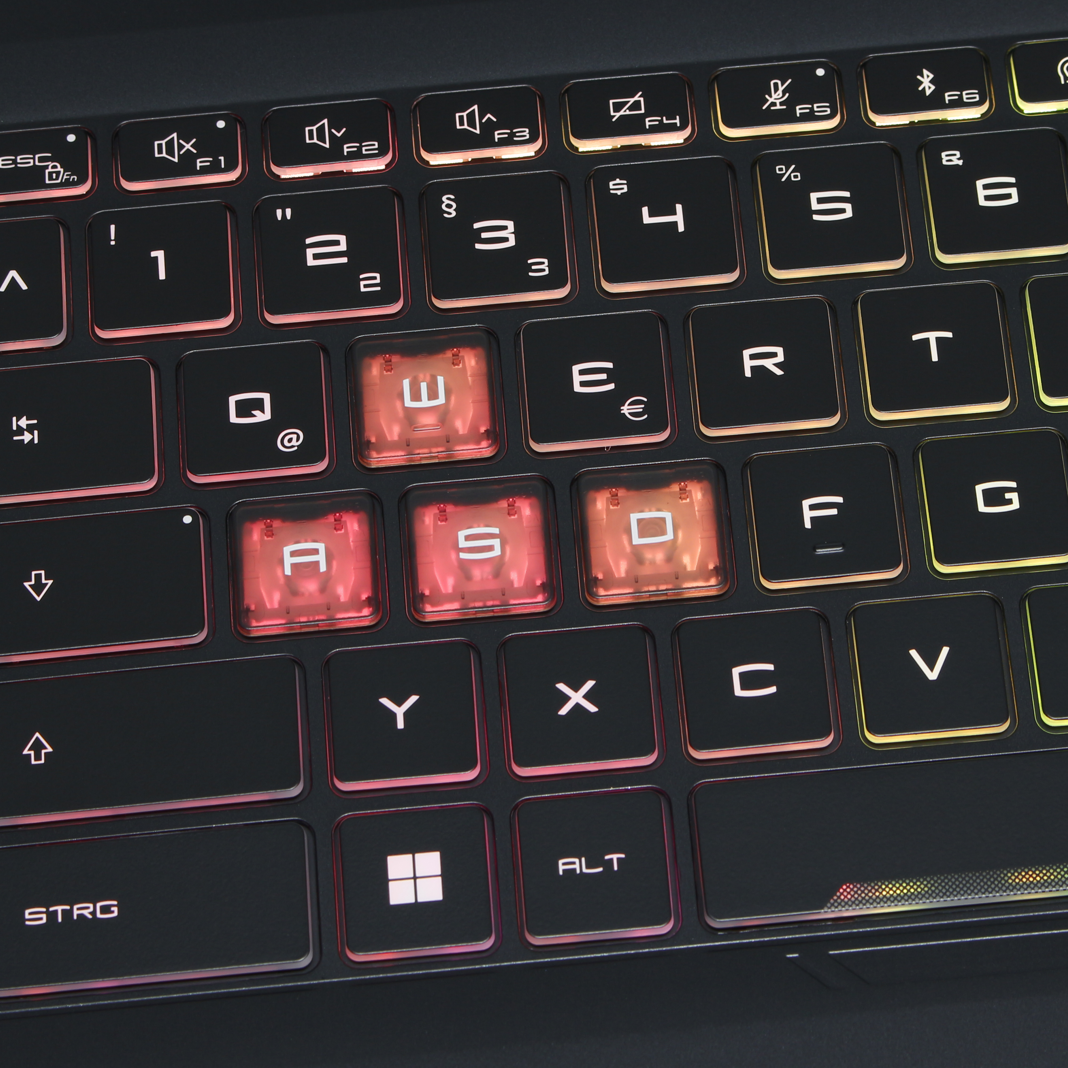 Zbliżenie czarnej klawiatury laptopa z podświetlanymi klawiszami. Klawisze WASD są podświetlone na czerwono.