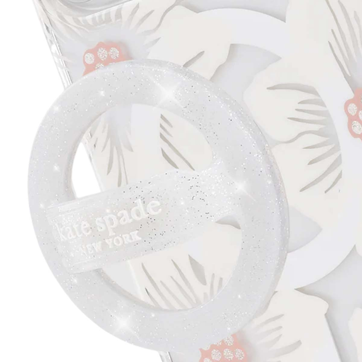 Una custodia trasparente con un anello glitterato bianco, logo 'kate spade new york' e design floreale su sfondo bianco.