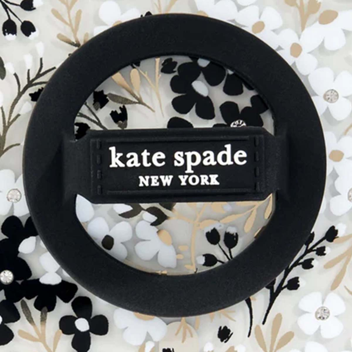 Impugnatura circolare nera per telefono con 'kate spade NEW YORK', sfondo floreale con fiori neri, bianchi e oro.
