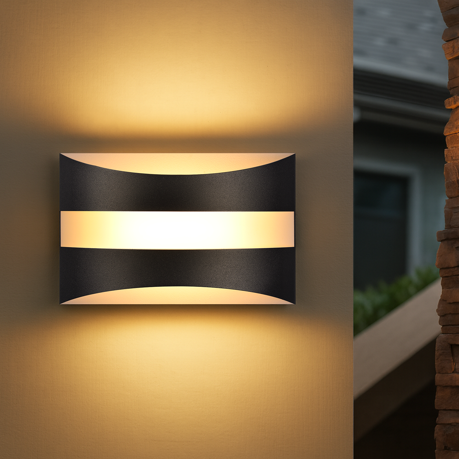 Un'applique da parete con un design nero curvo e una striscia luminosa orizzontale centrale e luminosa. È su un muro beige.