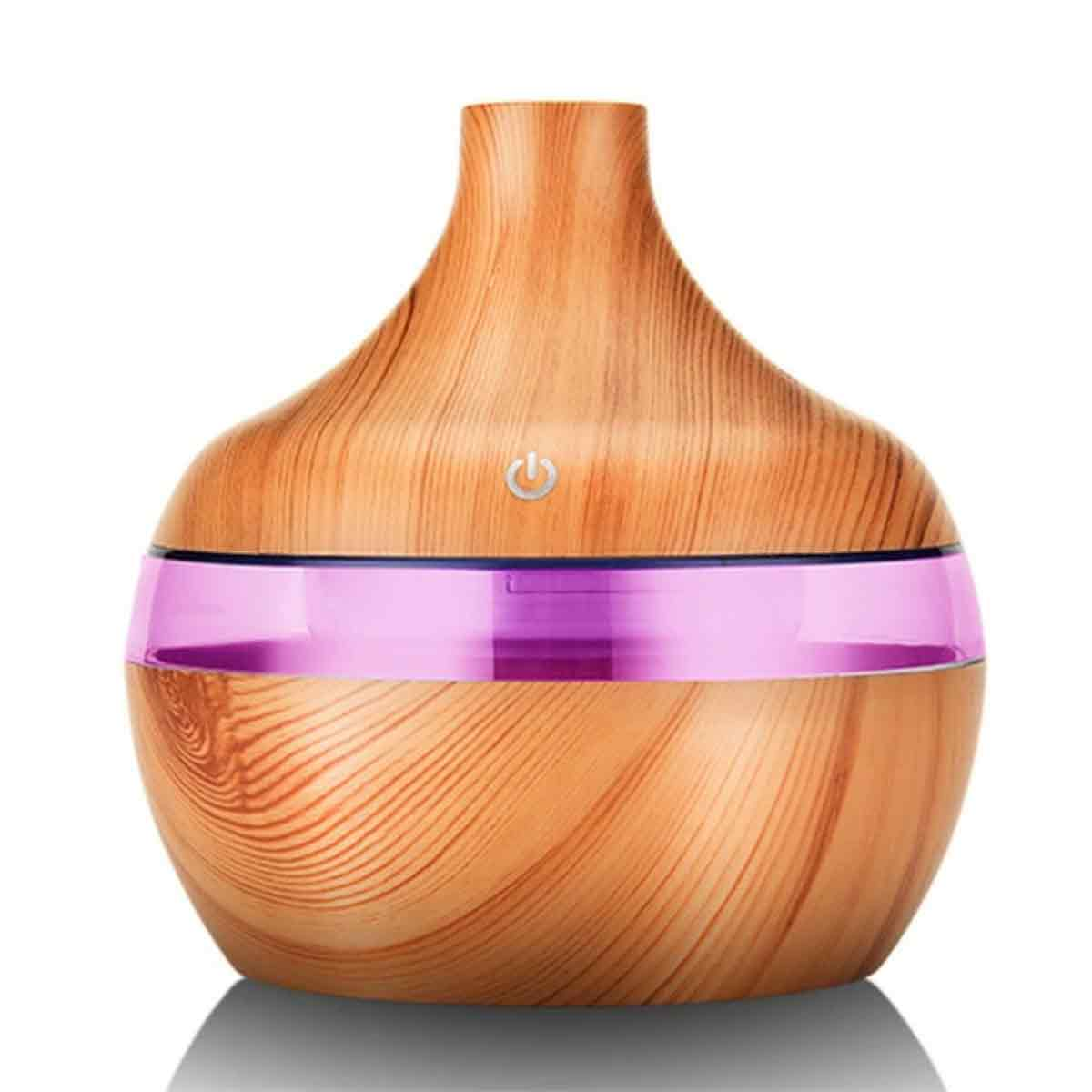 Ein Öldiffusor im Holz-Look mit einem lila Band. Er hat einen Ein-/Ausschalter und steht auf weißem Hintergrund.
