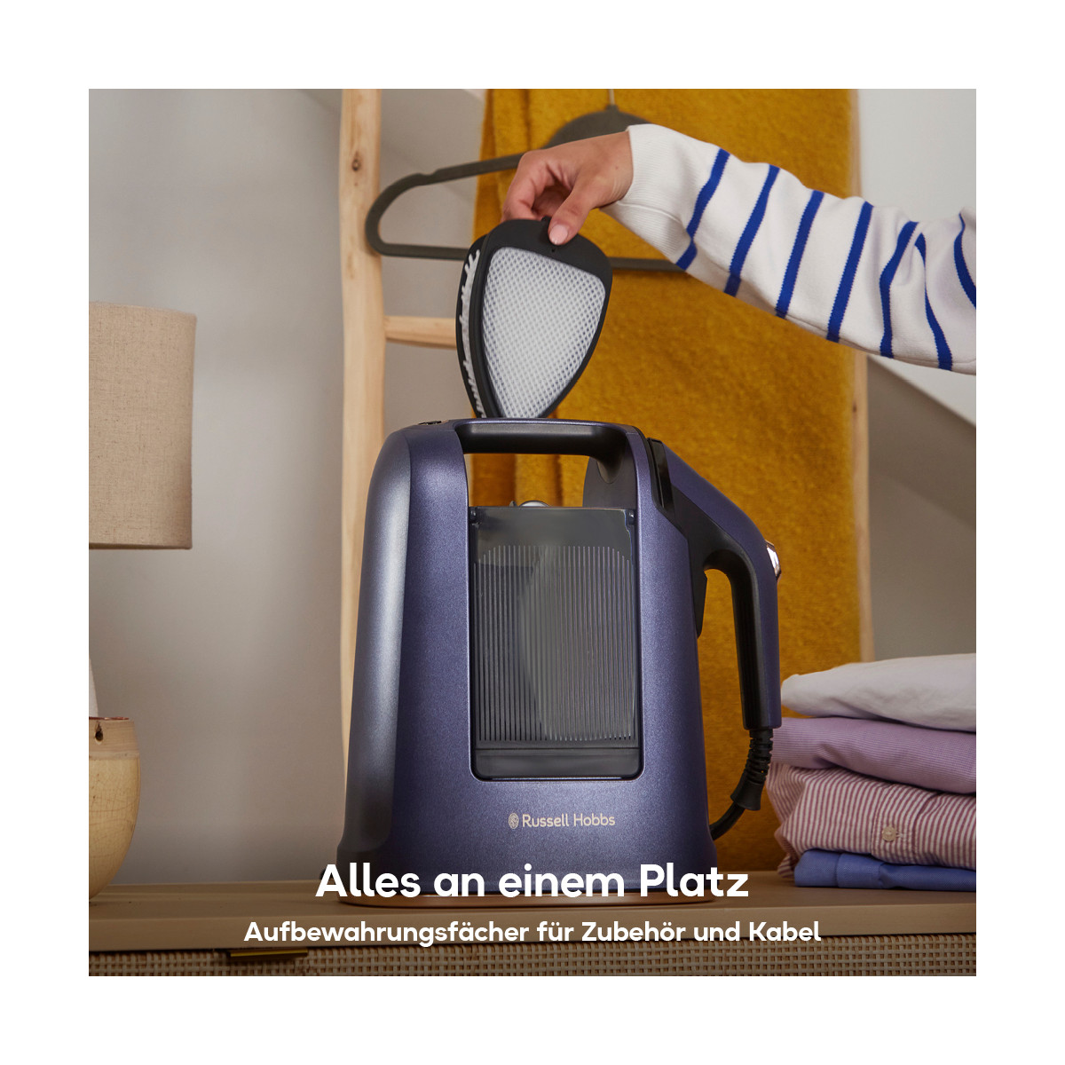 Une personne tient un accessoire de cuiseur vapeur au-dessus d'un cuiseur vapeur violet. Des vêtements empilés et une couverture jaune en arrière-plan.