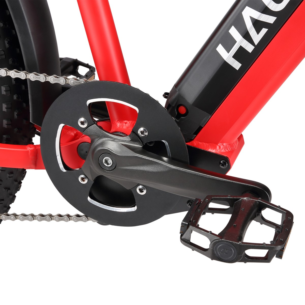 Zbliżenie na czerwoną ramę roweru z czarnymi elementami. Widoczny jest łańcuch, pedał i mechanizm korbowy. Rower ma czarny błotnik.