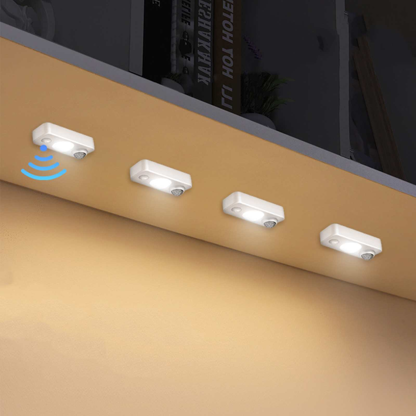 Vier weiße Lichter mit Bewegungssensoren sind unter einem Regal montiert. Ein Licht hat ein blaues Signal.
