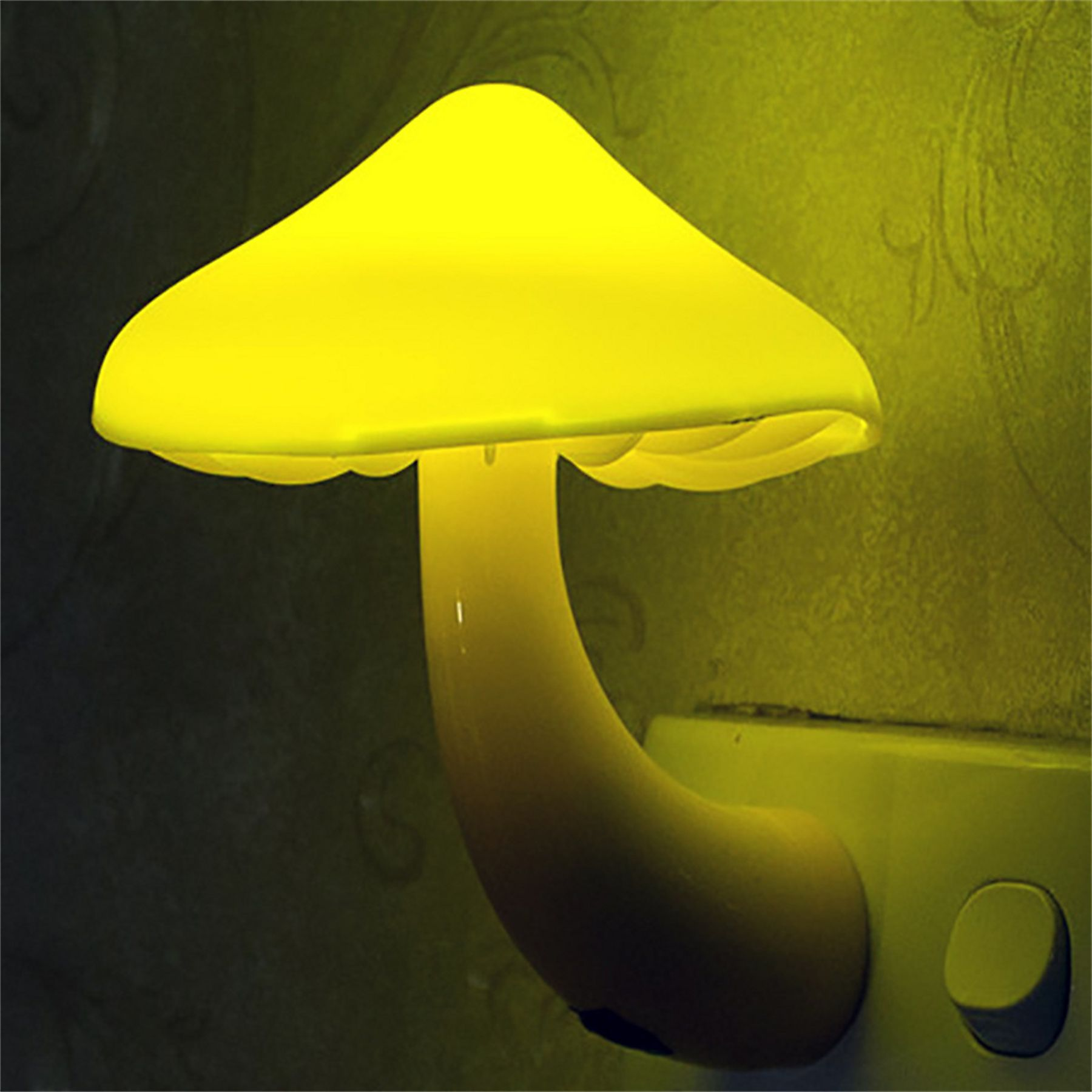Ein gelbes Pilz-Nachtlicht, das in eine Steckdose gesteckt ist. Der Hintergrund ist eine gemusterte Wand.