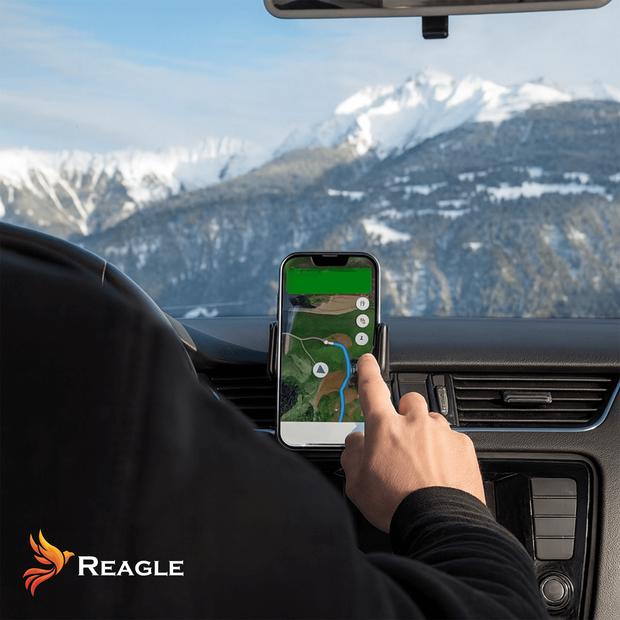 Ręka dotykająca telefonu z mapą w samochodzie. W tle widoczne są góry.