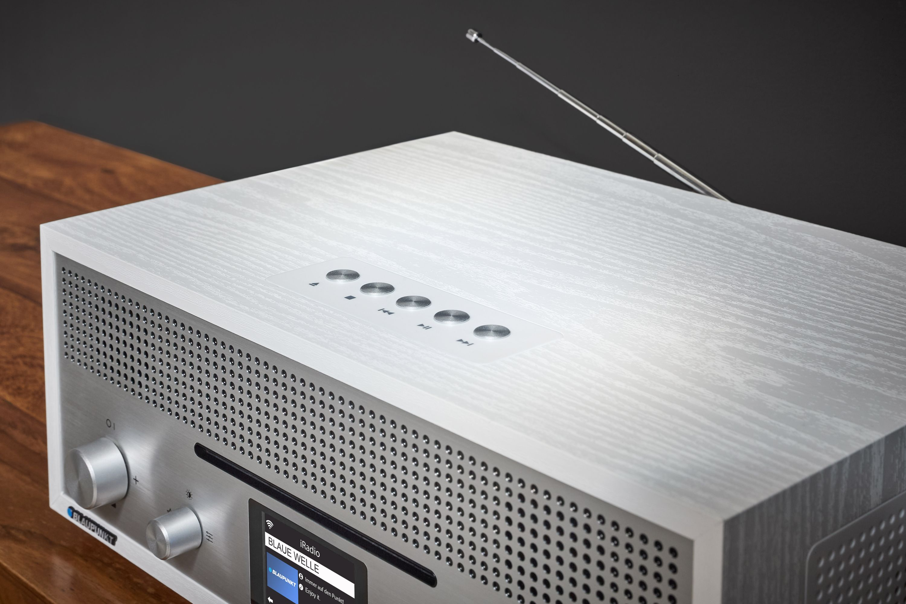 Ein weißes Blaupunkt-Radio mit silberner Antenne und Steuertasten. Es steht auf einer Holzoberfläche.